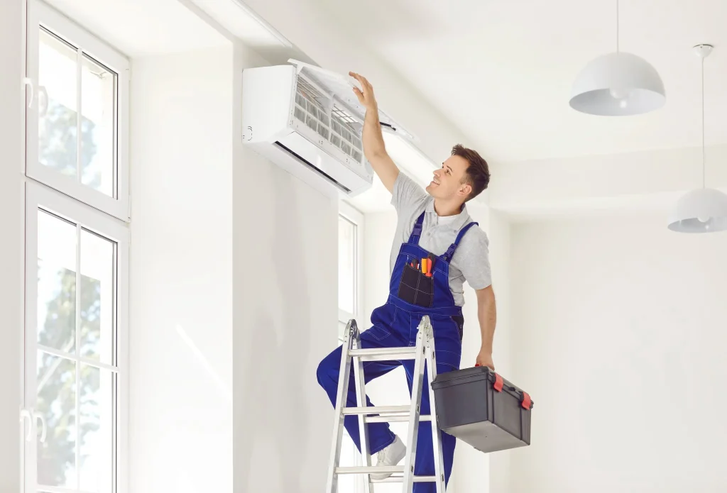 Technician in blue overalls working on an air conditioner unit
